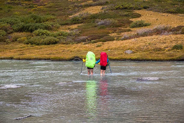 August 18, 2025. Russia. Altai Mountains. A group of tourists ford a mountain river.