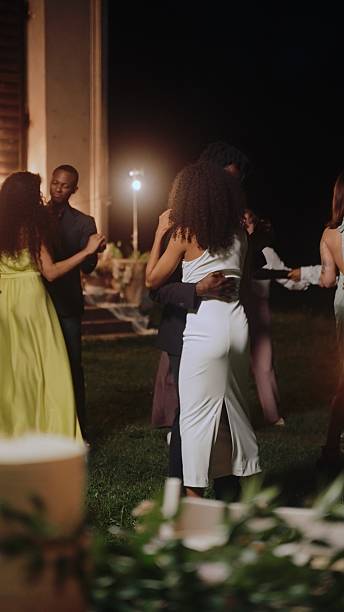 The bride and groom and their guests dance a slow dance among the guests near the ancient chapel at night