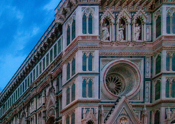 Ornate front facade of Florence Cathedral featuring intricate marble decoration and circular stained glass window at dusk.