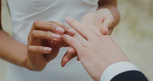 istock Bride puts wedding ring on grooms finger standing. 2256017189