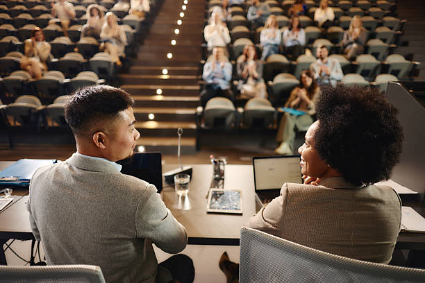 Back view of diverse business colleagues talking during a professional seminar in board room.