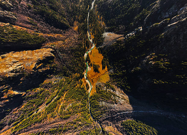 Aerial drone view of a forested gorge and emerald mountain river surrounded by orange cliffs. Sunny autumn in the mountains.