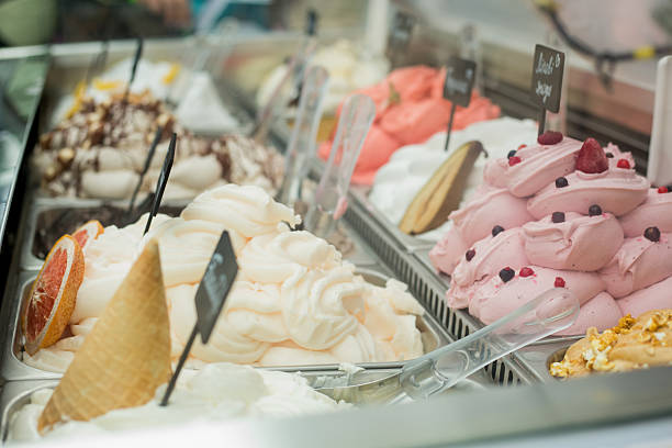 Ice cream display case featuring white vanilla with wafer cone, pink berry flavor, and assorted frozen treats with small signage