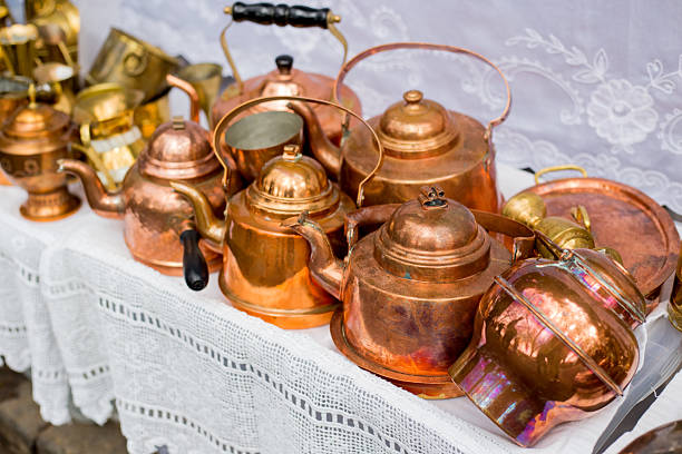 A collection of intricately designed golden and silver metal containers exhibited at the Souk Al Zel Market, showcasing traditional Arabian craftsmanship with an emphasis on elegance and cultural heritage.