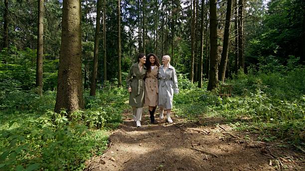 Three women with different skin colors are talking while walking in the forest