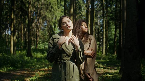 Two women of different nationalities pose standing in the forest