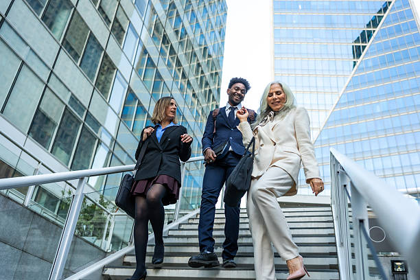 From below of confident businesspeople discussing while walking downstairs in city under clear sky during daytime