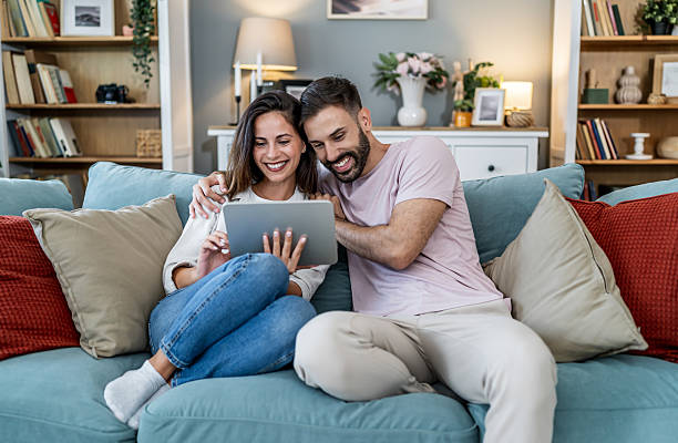 istock Happy couple relaxing on sofa using digital tablet 2256037558