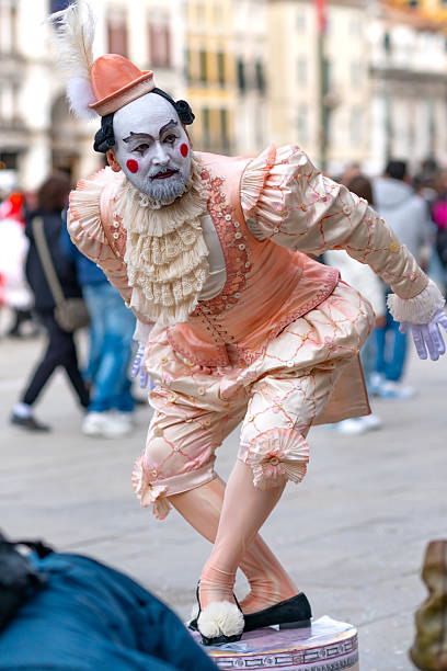 Venice, Italy - March 1, 2025: Mime performer in a pastel pink historical costume posing during the Venice Carnival on a city street