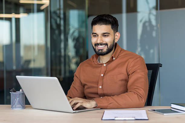 istock Smiling young man working efficiently on laptop in modern office 2256044616