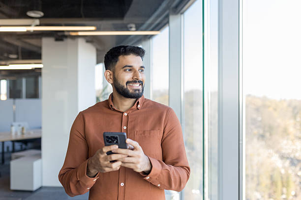 istock Indian businessman using smartphone and looking away in modern office 2256045342