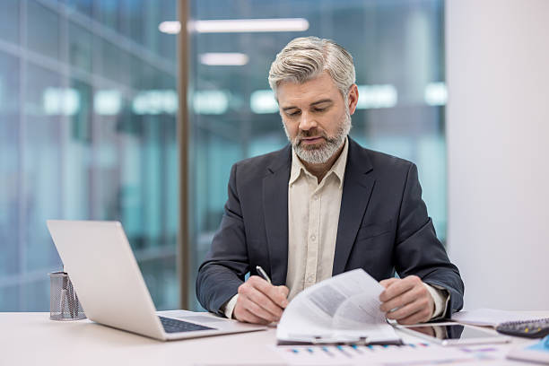 istock Mature businessman signing important contract documents in office 2256048185