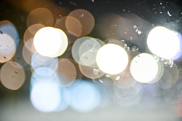 City bokeh lights through car glass with drops