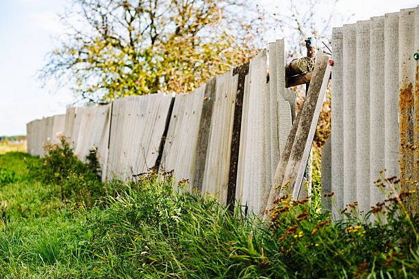 Old broken corrugated asbestos fence decaying and falling apart in a field