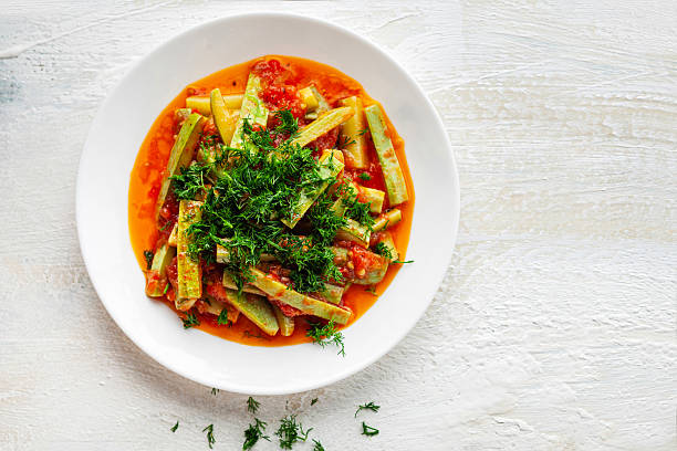 Traditional Turkish zucchini stew cooked with olive oil, tomatoes, and onions, served cold and topped with fresh dill. A healthy vegetarian Mediterranean dish presented on a white plate with natural light.