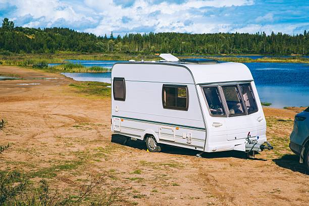A Serene Camping Scene Featuring a Classic Caravan by a Tranquil Lakeside Environment.