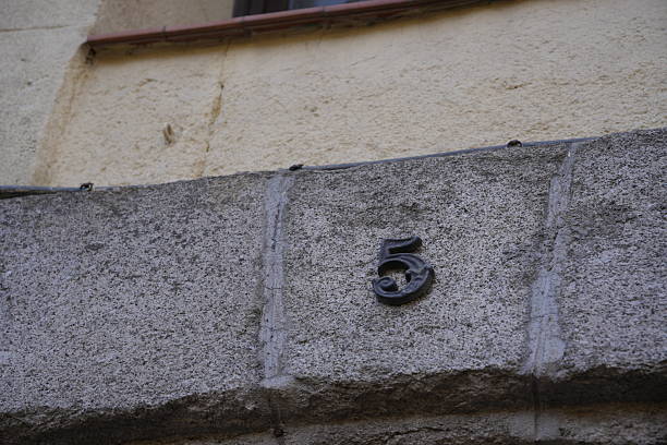Metal number five fixed to an ancient stone wall, indicating a street address