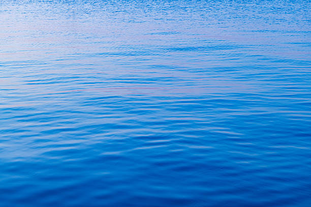 High-angle view of calm blue sea water texture. The surface features soft ripples and a natural gradient of blue tones, perfect for background use, summer themes, or nature-inspired designs.