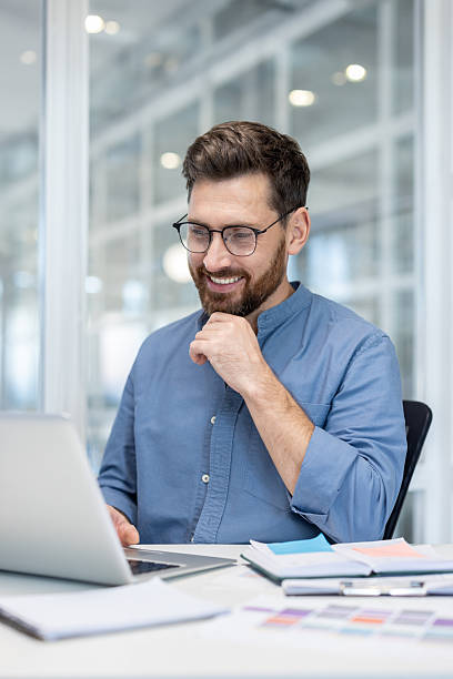 istock Smiling man working on laptop in modern office 2256074922