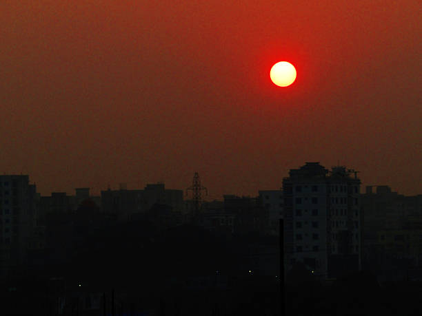 A soft, hazy sunset pours warm orange light over a quiet urban skyline. Silhouettes of rooftops rise along the horizon, creating a calm, atmospheric scene ideal for travel, lifestyle, or urban mood projects.