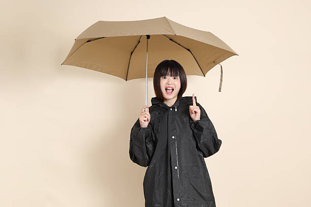 istock 20s Asian woman wearing raincoat 2256080614