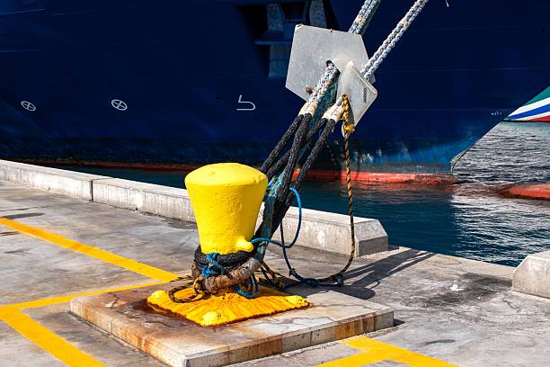 Yellow mooring post with rope on a dock, highlighting large ship in background