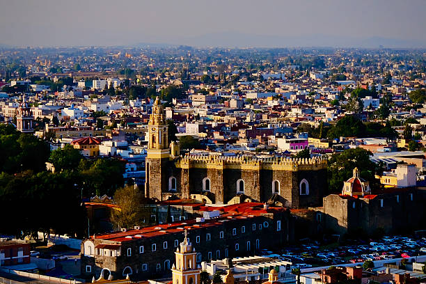 The historic stone walls and bell tower of the San Gabriel Convent stand prominently above the surrounding city buildings.