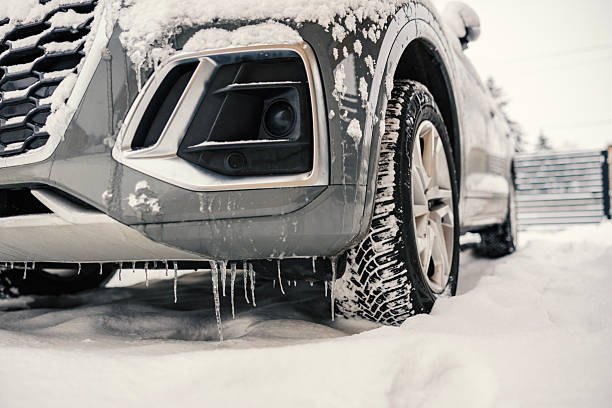 Muddy Dirty Icicles Forming Under Vehicle with Tire Detail - Winter driving and cold weather driving in SUV truck. Low angle view from ground level looking below. Wide angle and selective focus on dirty icicles.