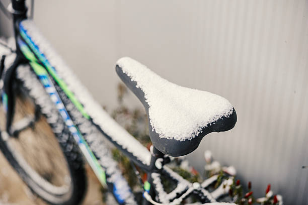 Bicycle saddle and frame blanketed in fresh white snow, a serene winter scene of cold, quiet outdoors with the bike resting unused in pristine frosty silence