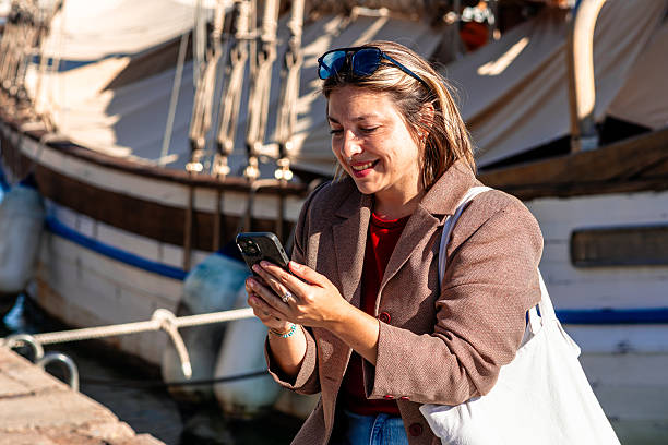 istock Woman smiling using smartphone at barcelona port 2256090010