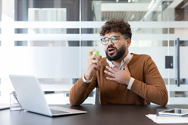 istock Man spraying throat in office due to sore throat 2256091437