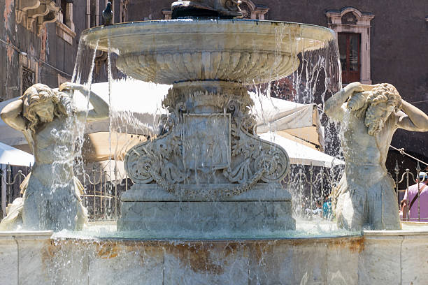 Catania, Italy-May 14, 2022:TMythological characters on the Amenanoa fountain by Tito Angelini and engraving of the city coat of arms during a day in May