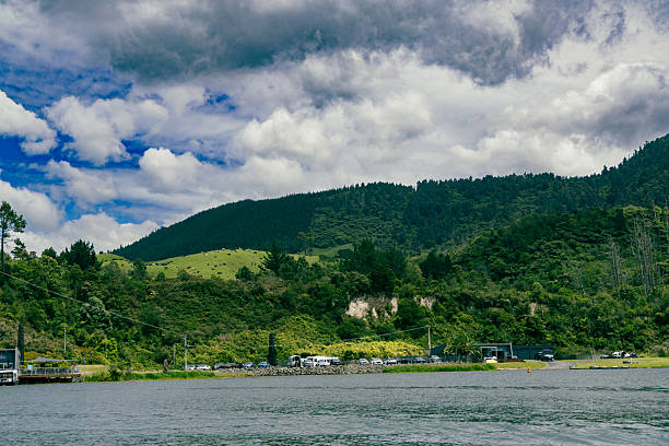 Clouds gather above forested slopes near water forest trees meadow pasture