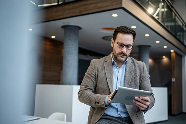 istock Businessman sitting checking digital tablet in modern office 2256097678