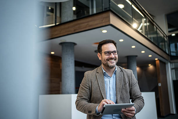 istock Smiling businessman using tablet in modern office lobby 2256097682