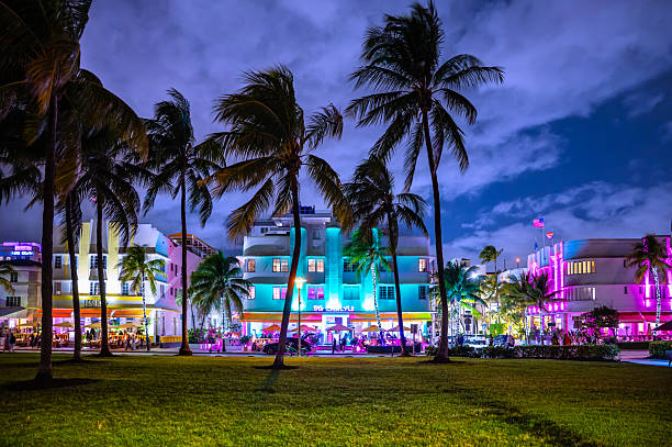 Miami Beach, Florida, USA - Nov 11, 2025: Nightlife and Art Deco Buildings of Ocean Drive in South Beach. Swaying Palm Trees in the Front. Colorful Neon Lights.