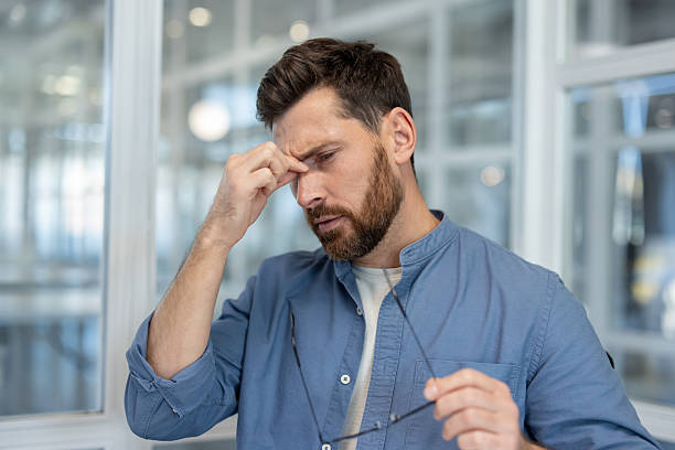 istock Stressed man suffering from headache and eye strain in office 2256107944