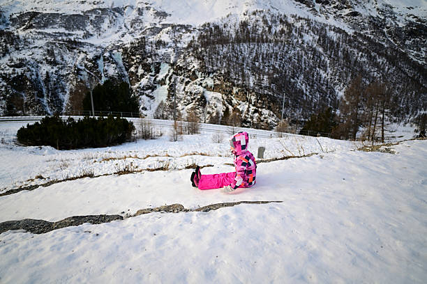 Child playing on snow sitting on winter mountain slope