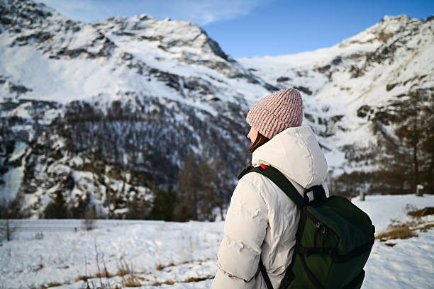 Woman wearing a beanie and warm coat looking at snowy mountains