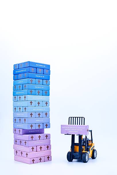 Wonderful multi color tower of wooden blocks with Bible references printer on the side of the blocks.  Forklift lifting one block show a verse on the flat side of the block.