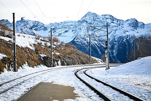 Railway tracks curving through snowy mountains in Swiss Alps