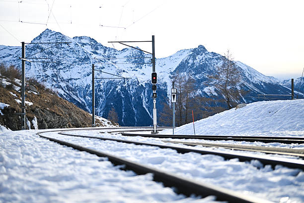 Train tracks curving through snowy Alps mountains in winter