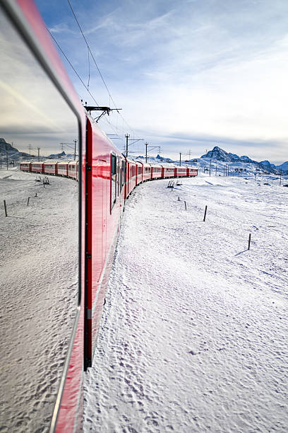 Red Bernina Express train traveling through a snowy mountain landscape in winter