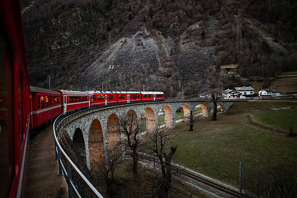 Red train on Brusio viaduct, a railway engineering marvel in the Swiss Alps