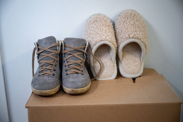 Cozy home still life with suede lace up boots and soft wool slippers on cardboard storage box