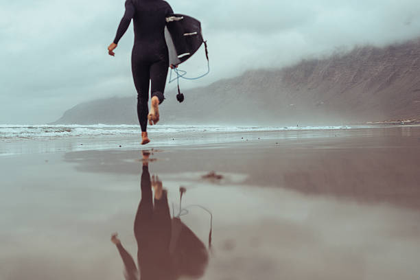 Young woman is exiting ocean after windsurfing