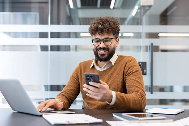 istock Young man using smartphone and laptop in office 2256121437