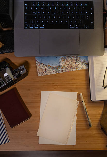 High angle view of a creative workspace with laptop, vintage camera, and map.