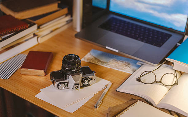 Creative workspace with analog camera, notebook and laptop on wooden desk