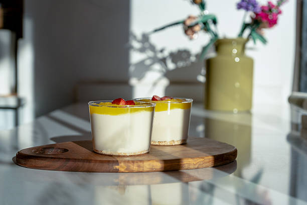 Mango magnolia dessert with creamy layers, topped with fresh strawberry slices, served in glass cups and photographed in natural light.